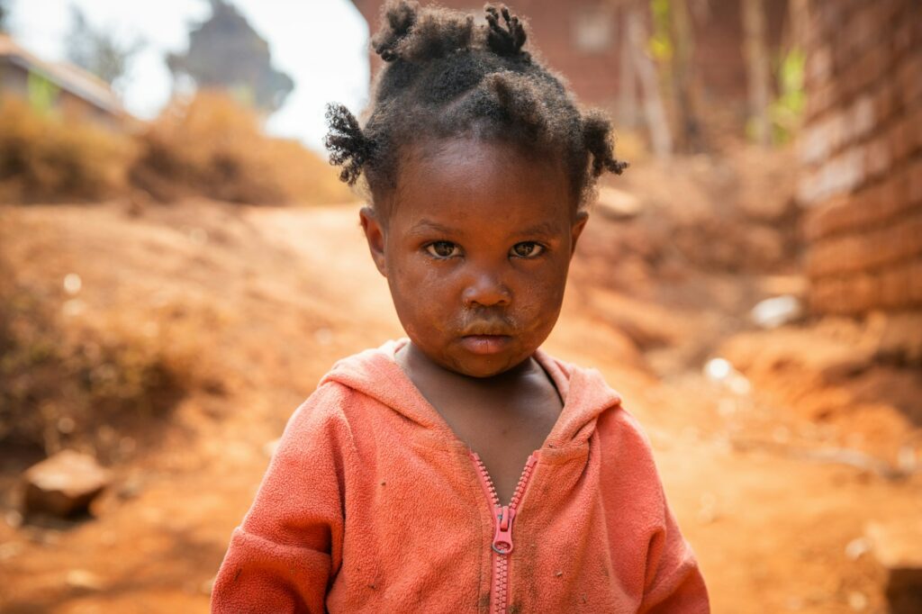 Poor little girl wearing dirty clothes in an African village,